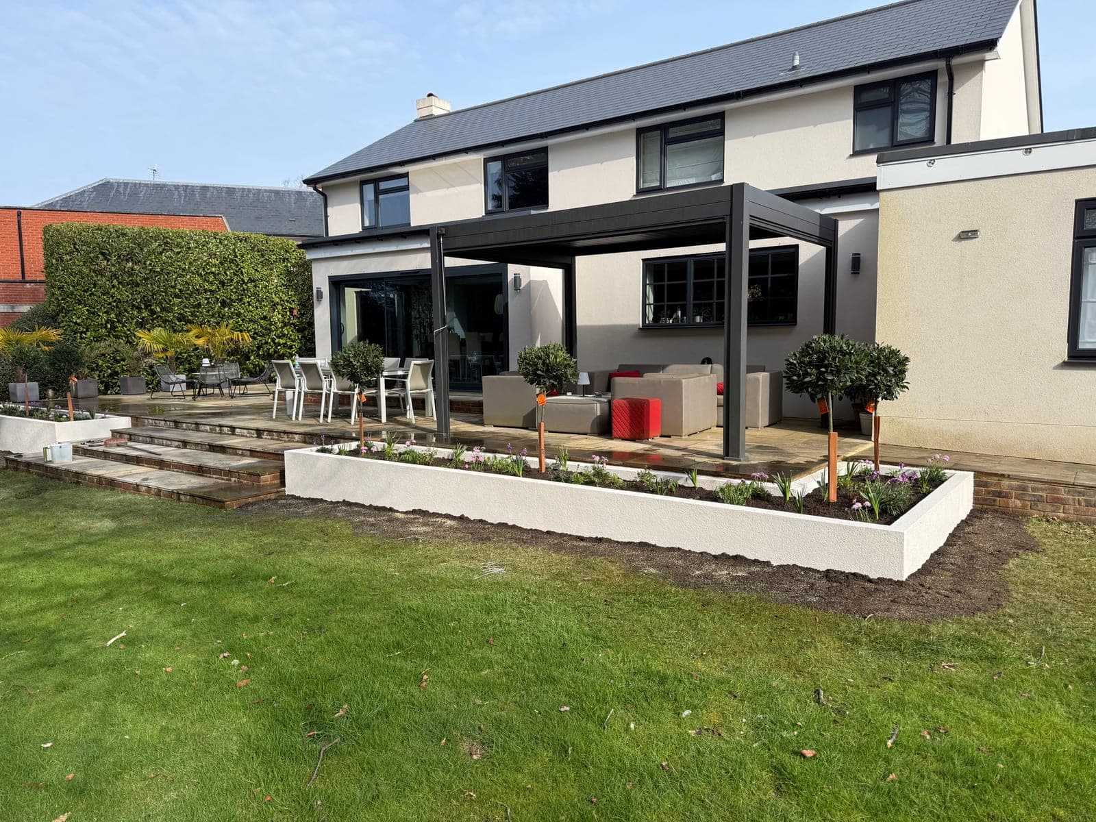 Completed landscape project by Gemzas Garden Maintenance and Landscaping with rendered raised beds, stone terrace and pergola seating
